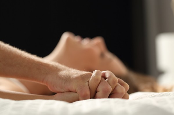 Close up profile of a couple having sex on a bed at home in the night